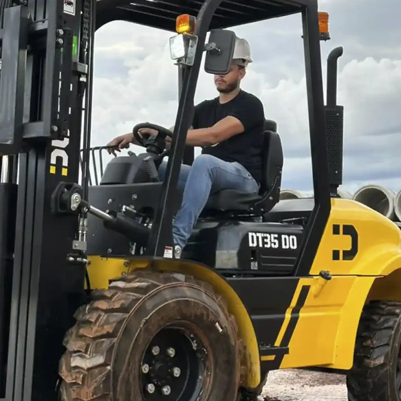 Empilhadeira Off-Road Dutt DT35 DO transportando tubos de concreto em canteiro de obras, destacando pneus de alta tração e design para terrenos irregulares