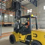 Empilhadeira Dutt DT35D com mastro triplex estendido realizando empilhamento vertical de carga em porta-pallets, demonstrando estabilidade e altura de elevação