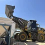 Pá carregadeira Dutt DT806 com braço de elevação totalmente estendido descarregando material em silo de concreto da Alfa Norte, céu limpo ao fundo