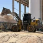 Vista lateral da pá carregadeira Dutt DT806 despejando areia em um alimentador de usina de concreto, demonstrando alcance e altura de descarga